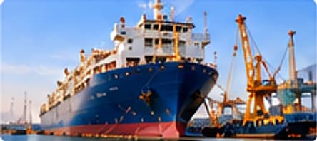 Livestock carrier ship at an Omani quay with port cranes at sunset